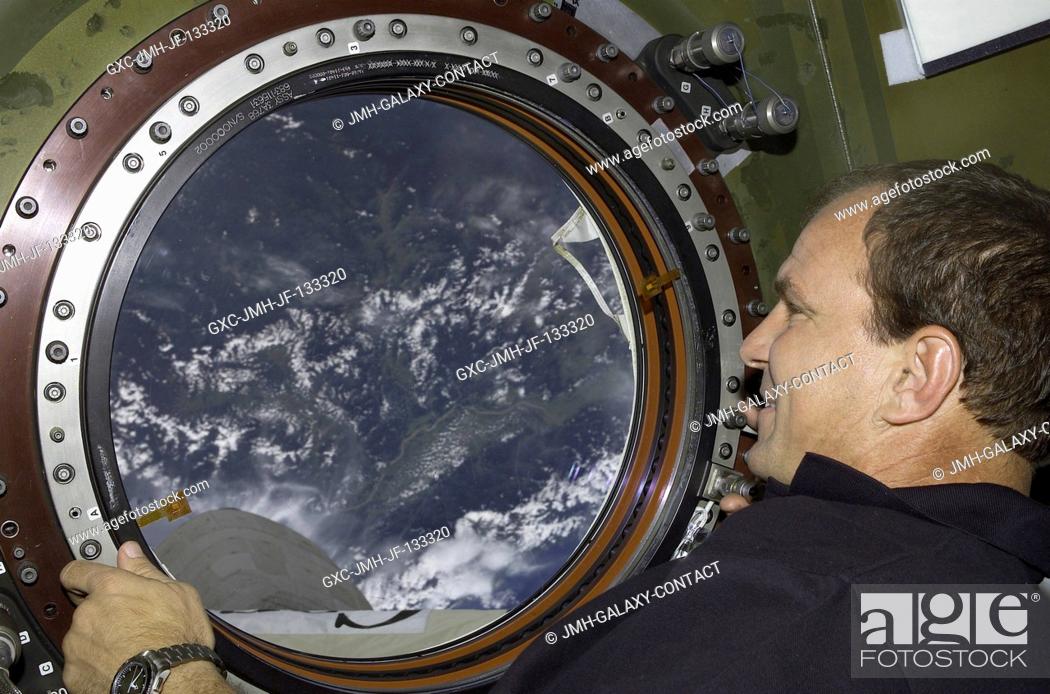 Stock Photo: Astronaut Michael J. Bloomfield, STS-110 mission commander, looks through the Earth observation window in the Destiny laboratory on the International Space.