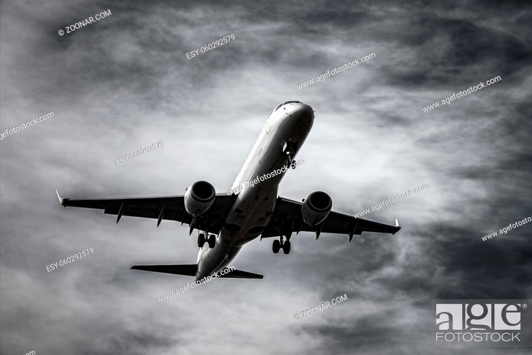 Stock Photo: Flugzeug im Landeanflug vor dramatischem Himmel in Schwarz Weiss. Airplane landing in front of dramatic sky in black and white.