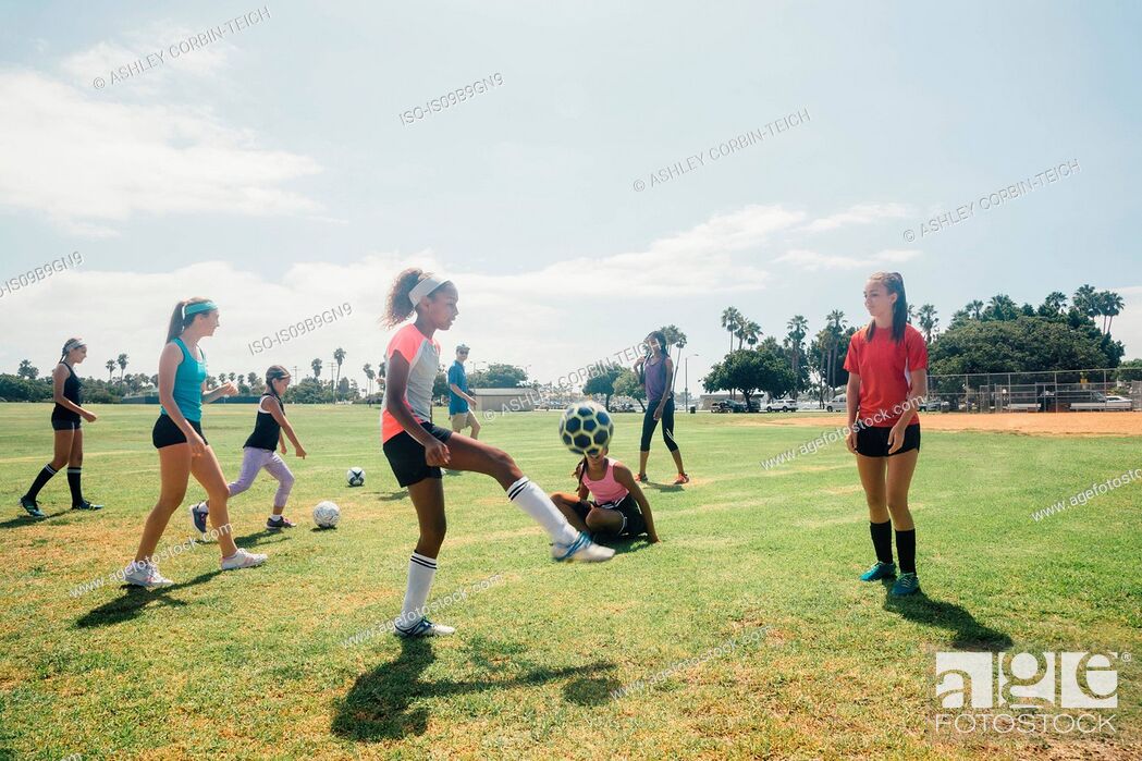 Stock Photo: Schoolgirls practicing keepy uppy with soccer ball on school sports field.