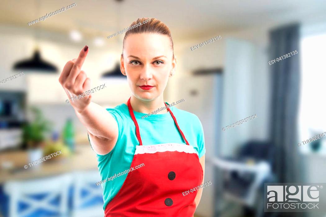 Imagen: Wife or maid showing middle finger on indoor background wearing red cleaning apron.
