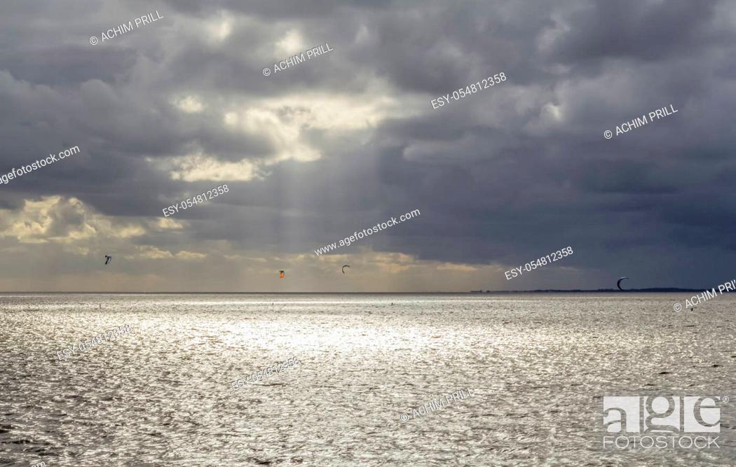 Stock Photo: dramatic illuminated coastal scenery including some kitesurfers near Neuharlingersiel in Eastern Frisia, Germany.