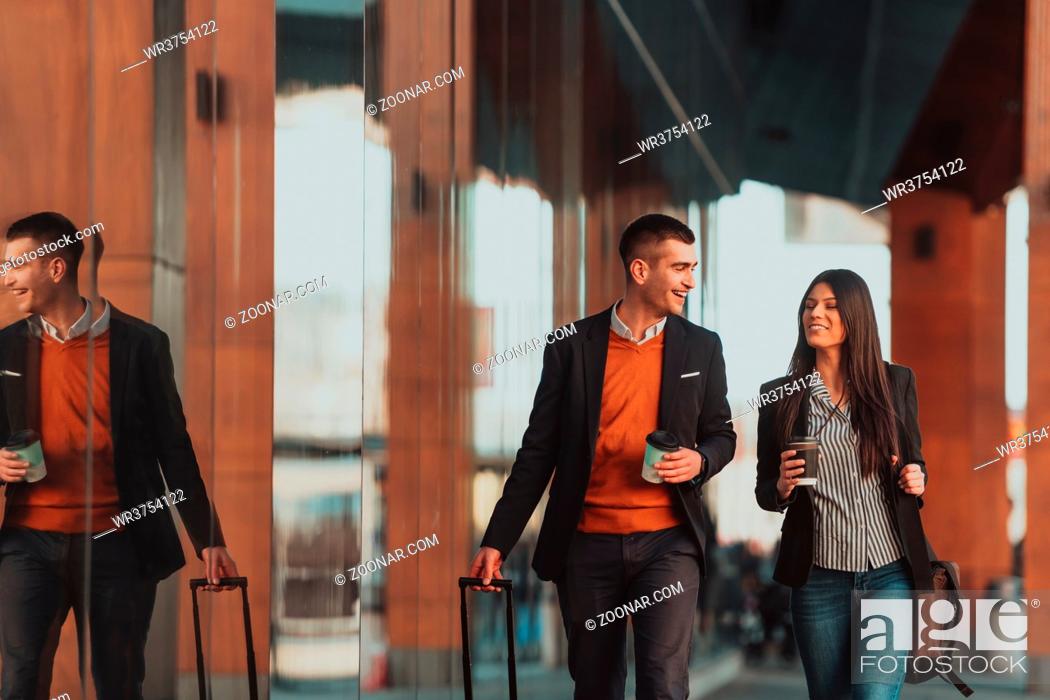 Stock Photo: Businessman and businesswoman talking and holding luggage traveling on a business trip, carrying fresh coffee in their hands. Business concept.