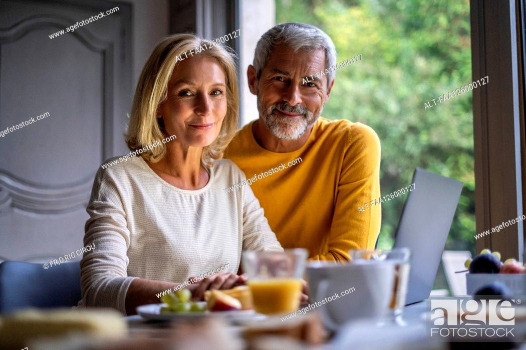 Stock Photo: Portrait of smiling mature couple using laptop at home.
