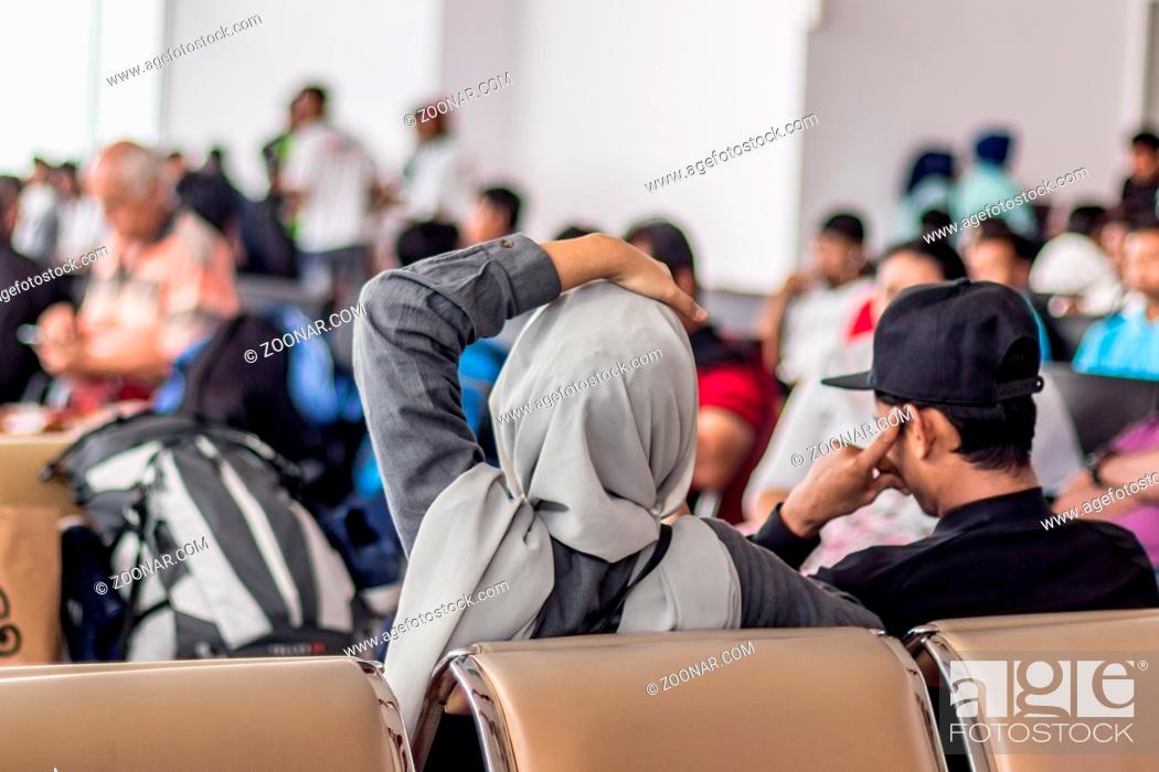 Photo de stock: Modern muslim islamic asian couple sitting and waiting for flight departure at international airport terminal.