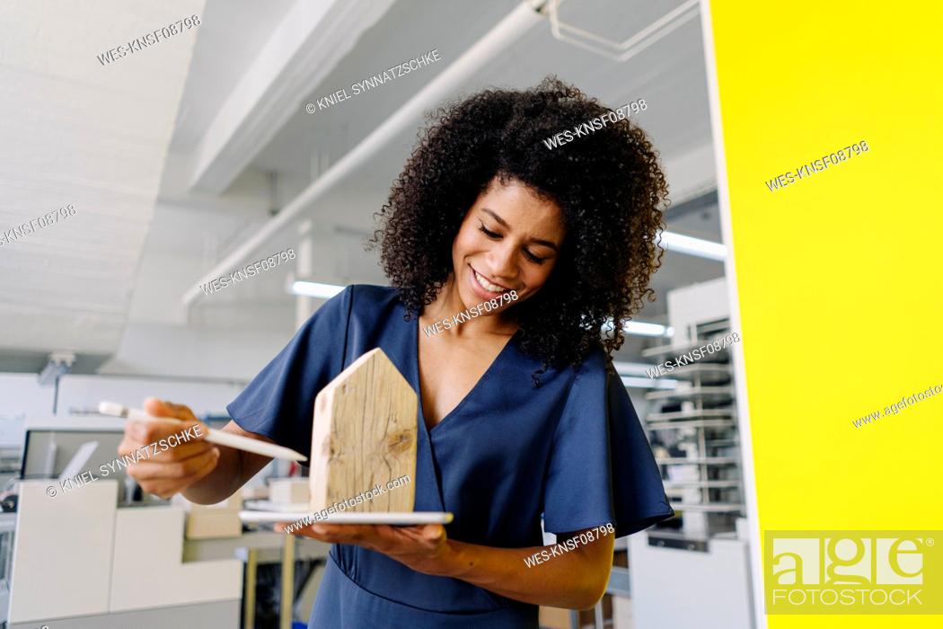 Stock Photo: Smiling female real estate agent examining house model in agency.