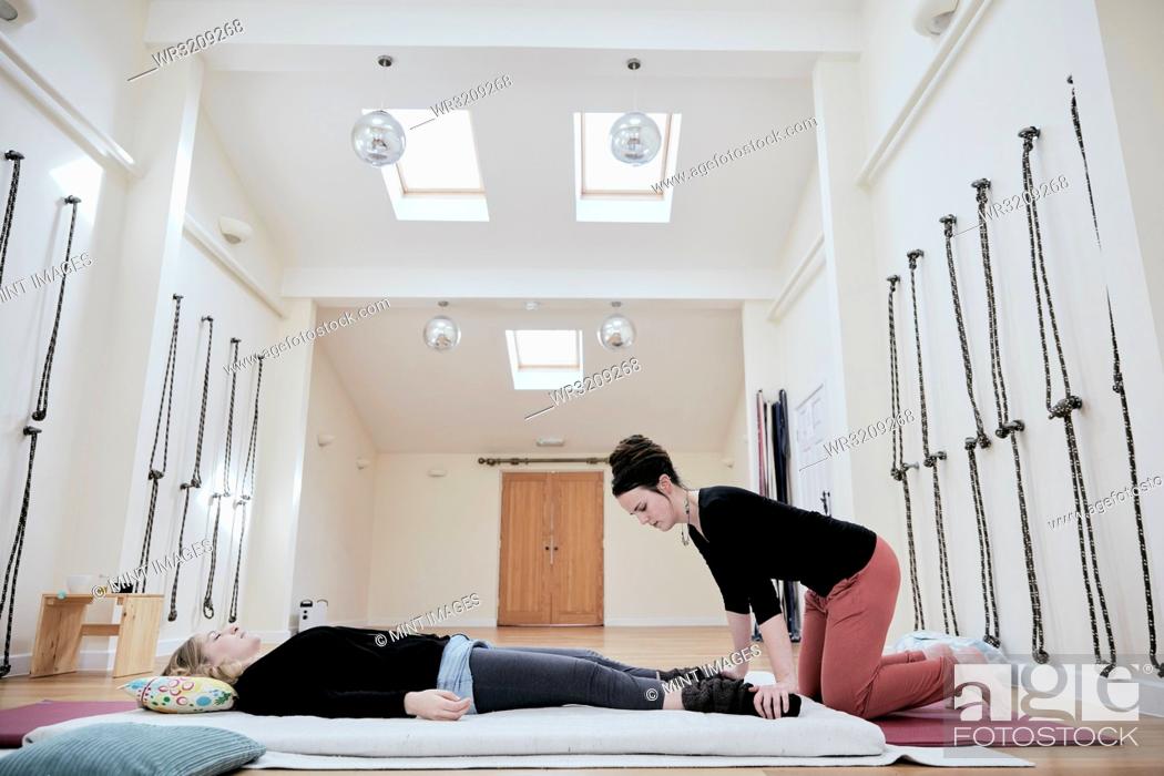 Stock Photo: Woman lying down fully clothed having a Thai massage in a light filled exercise studio.