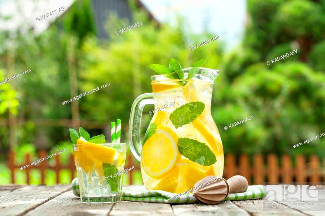 Stock Photo: Lemonade pitcher with lemon, mint and ice on garden table.