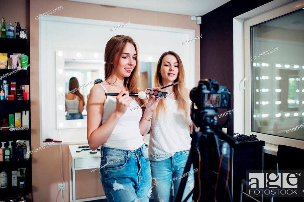 Imagen: Two friends doing a makeup products review shooting a video blog standing in front of camera.