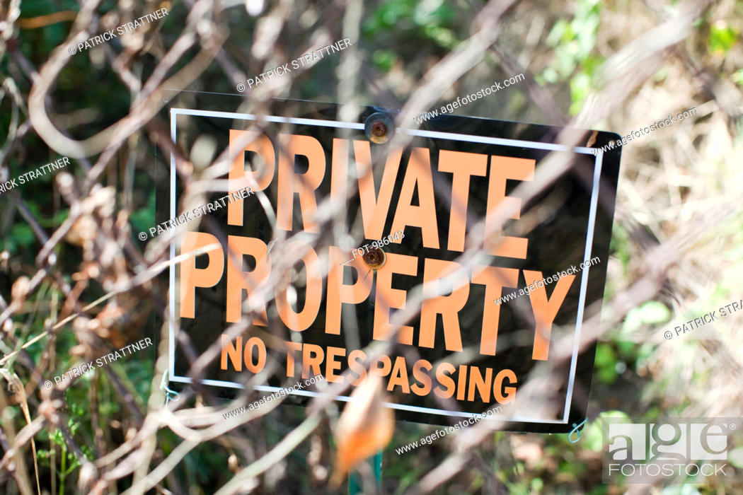 Stock Photo: A NO TRESPASSING sign behind a chain-link fence.