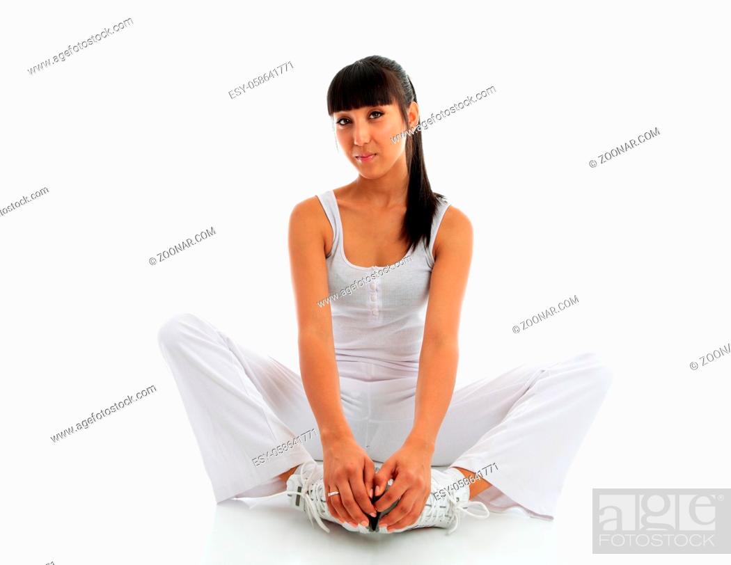 Imagen: A young woman wearing fitness sportswear. She is doing a groin and inner thigh stretch sitting on the floor with feet together and using effort to push knees to.