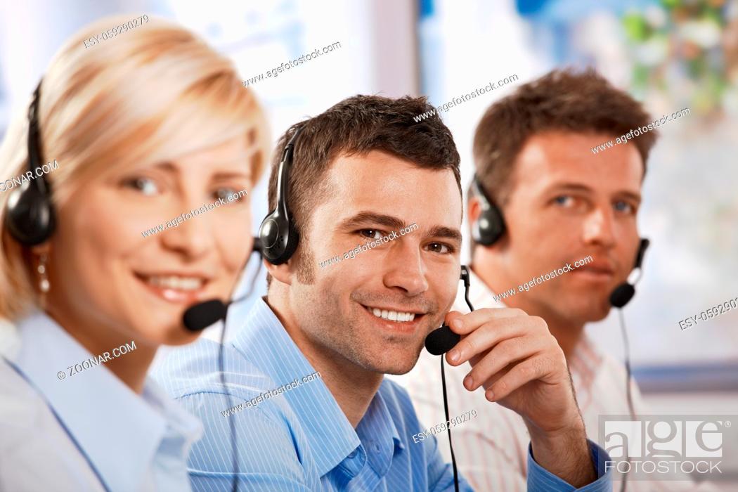 Stock Photo: Happy young customer service operators talking on headset, eye contact, smiling.