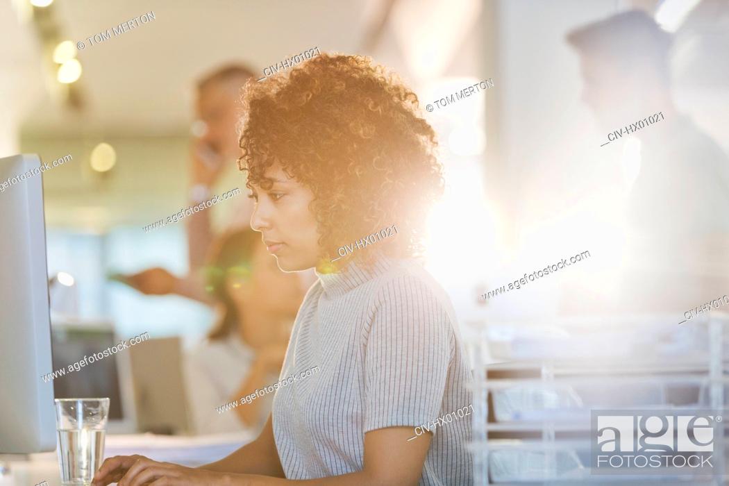 Stock Photo: Focused businesswoman working at computer in sunny office.