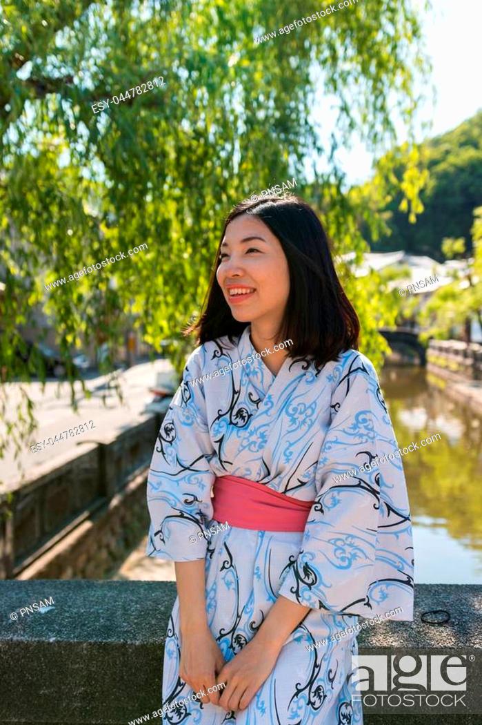Stock Photo: an asian young woman smiling and wearing Yukata, Japanese traditional clothes, under the tree.