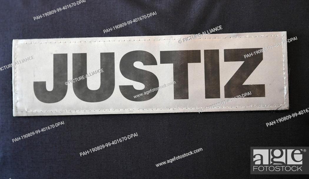 Stock Photo: 09 August 2019, Baden-Wuerttemberg, Freiburg: The sign of a magistrate standing in the courtroom of the district court is attached to his clothes.