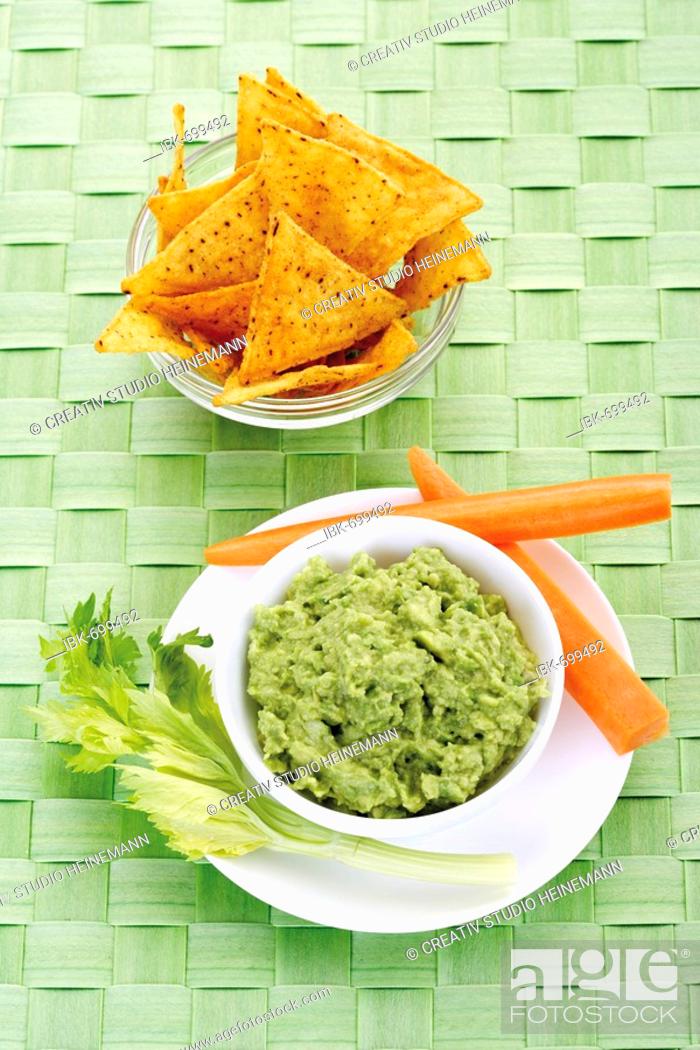 Photo de stock: Nachos and avocado dip (guacamole) garnished with carrots and celery.