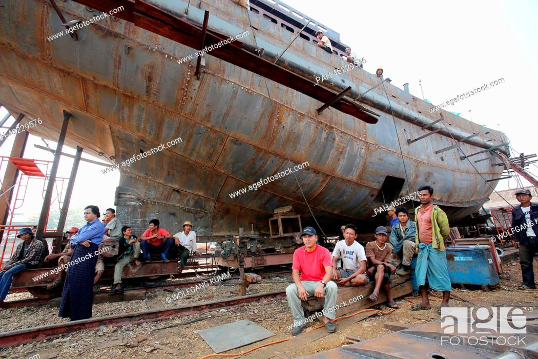 Stock Photo: Dock workers sit in front of a vessel under construction during a baptism ceremony of a converted passanger boat, called the 'Swimming Doctors 2' (not in.