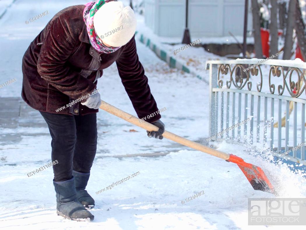Stock Photo: working woman cleans snow shovel in the nature .