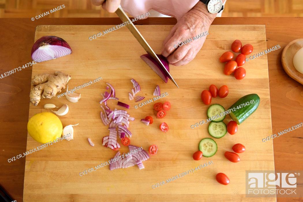 Stock Photo: Overhead of woman cutting onions and fresh vegetables on block.