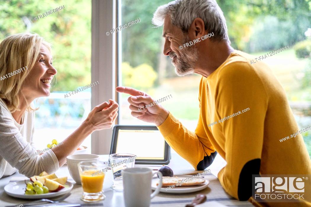 Photo de stock: Smiling mature couple talking with each other while having breakfast.