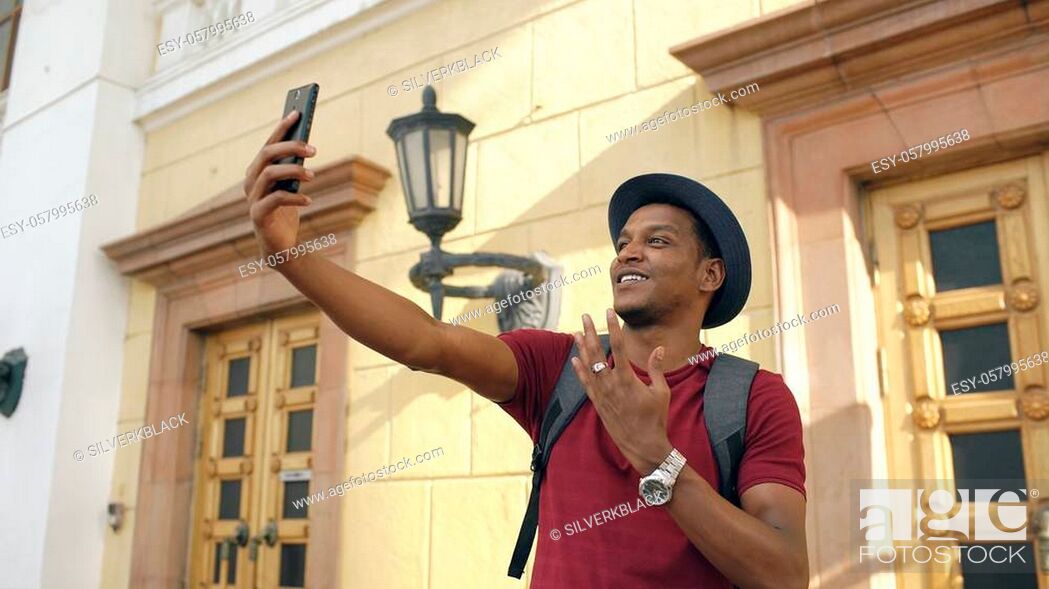 Stock Photo: African american tourist man having online video chat using his smartphone while travelling in European country.