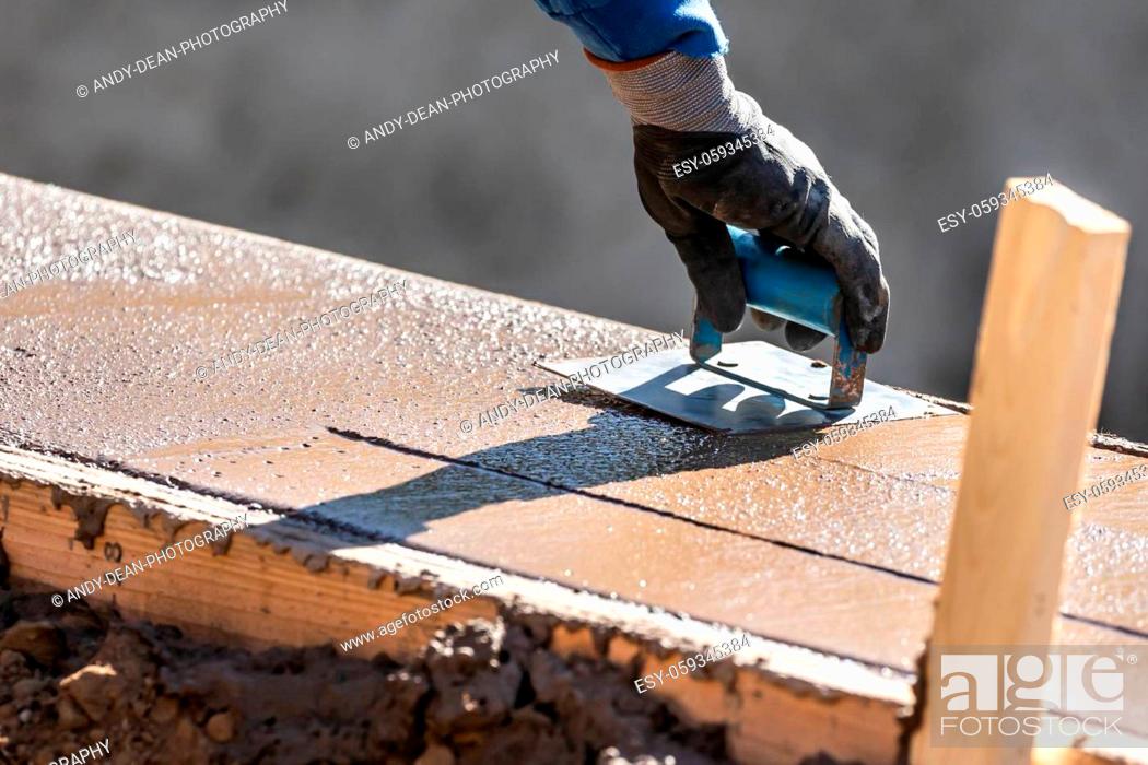 Stock Photo: Construction Worker Using Hand Groover On Wet Cement Forming Coping Around New Pool.