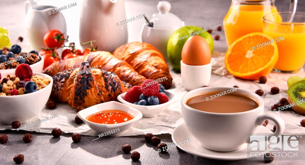 Stock Photo: Breakfast served with coffee, orange juice, croissants, egg, cereals and fruits. Balanced diet.
