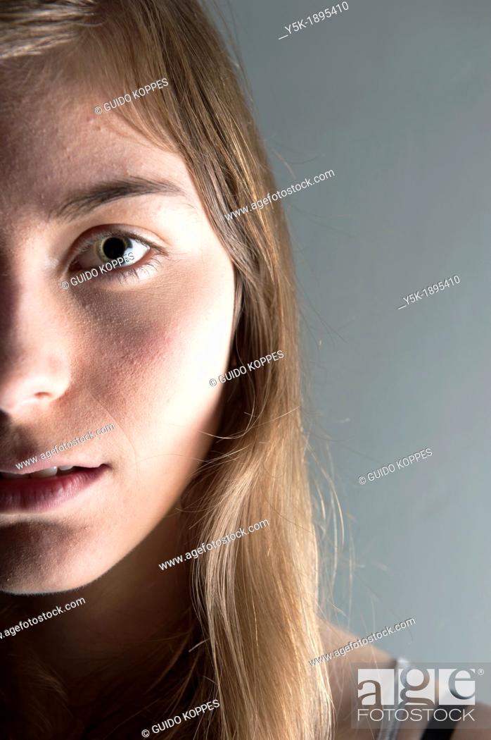Stock Photo: Tilburg, Netherlands. Studio-portrait of a young woman against a grey background. Detailed image.