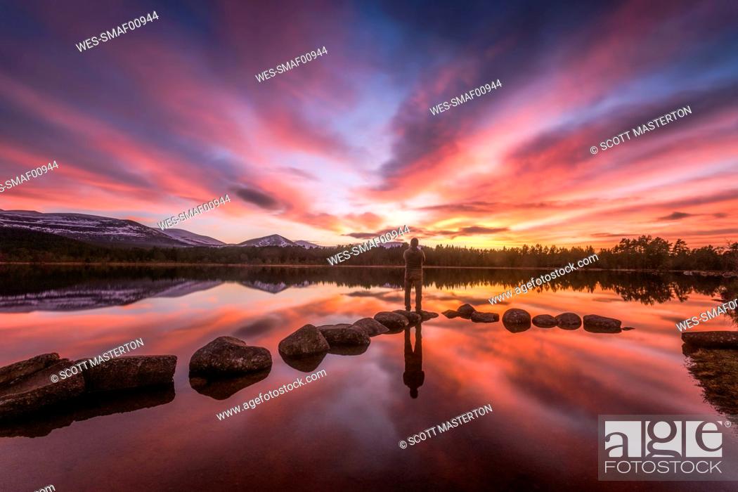Stock Photo: United Kingdom, Scotland, Highlands, Cairngorms National Park, Loch Morlich, sunset, hiker standing on stone.