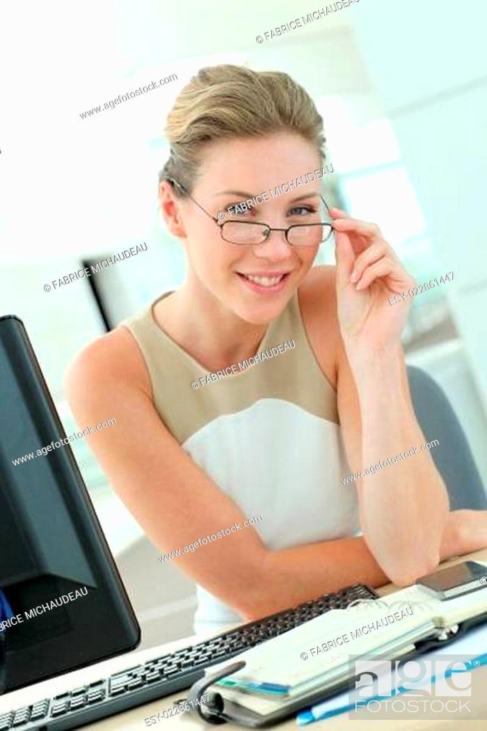 Stock Photo: Beautiful businesswoman with eyeglasses sitting in office.