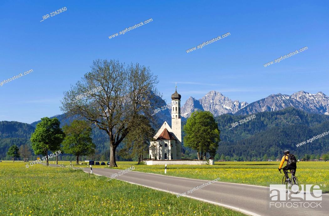 Stock Photo: Cyclist on the road to the pilgrimage church of St. Coloman, Schwangau near Fuessen, Bavarian Alps, Allgaeu, Upper Bavaria, Bavaria, Germany, Europe.