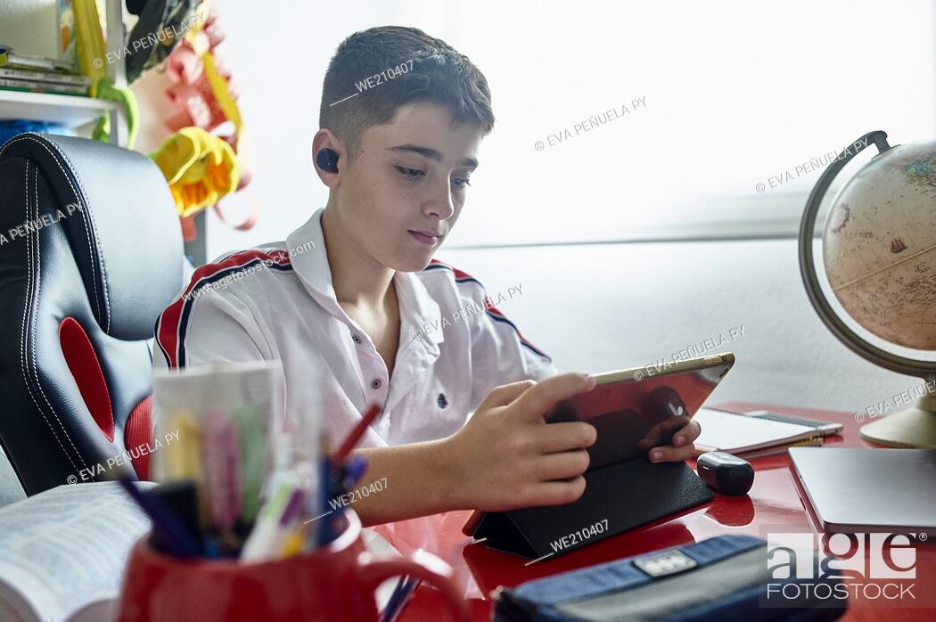 Stock Photo: teenager teaching online classes and doing his homework in his study room.