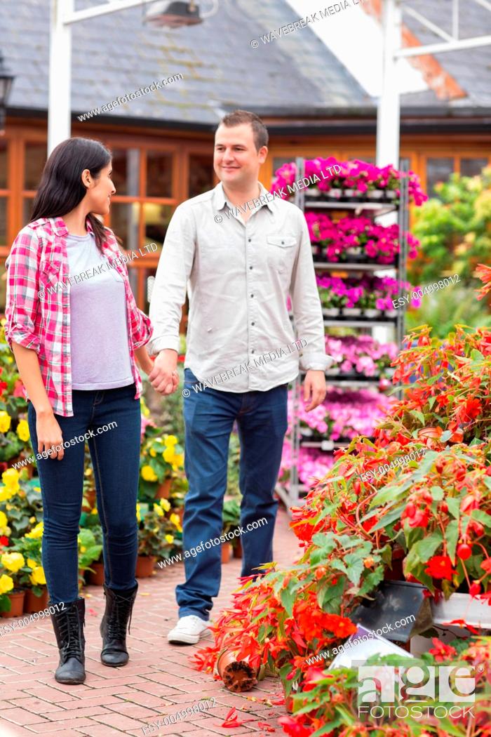 Stock Photo: Couple walking in garden centre while smiling and holding hands.