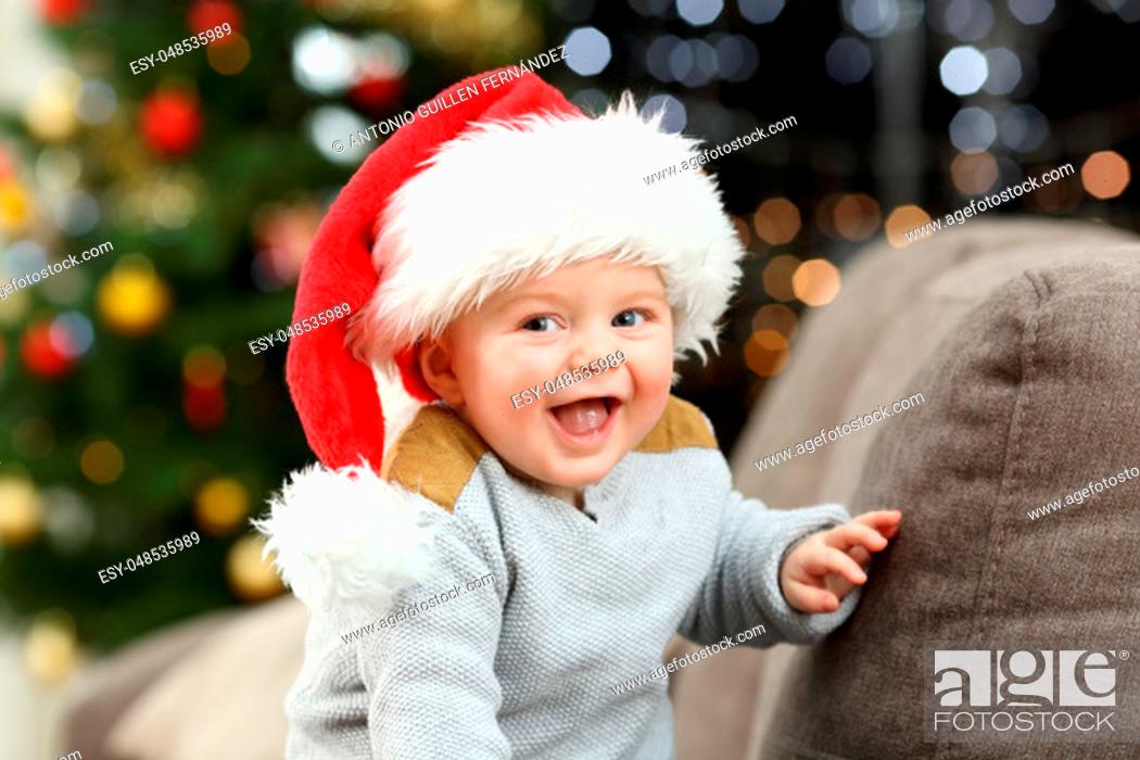 Stock Photo: Joyful baby looking at camera in christmas on a couch in the living room at home.