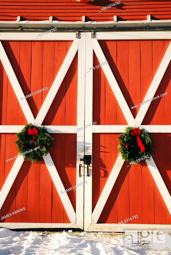 Stock Photo: Christmas wreathes hand on a barn door.