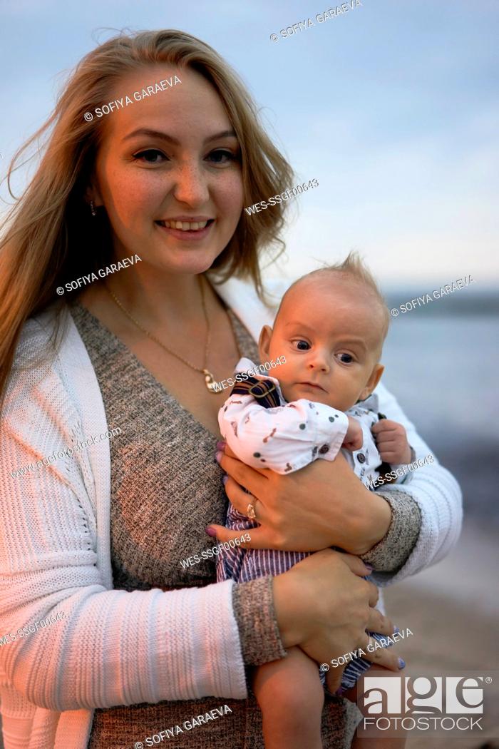 Stock Photo: Happy mother with cute baby boy on beach at sunset.