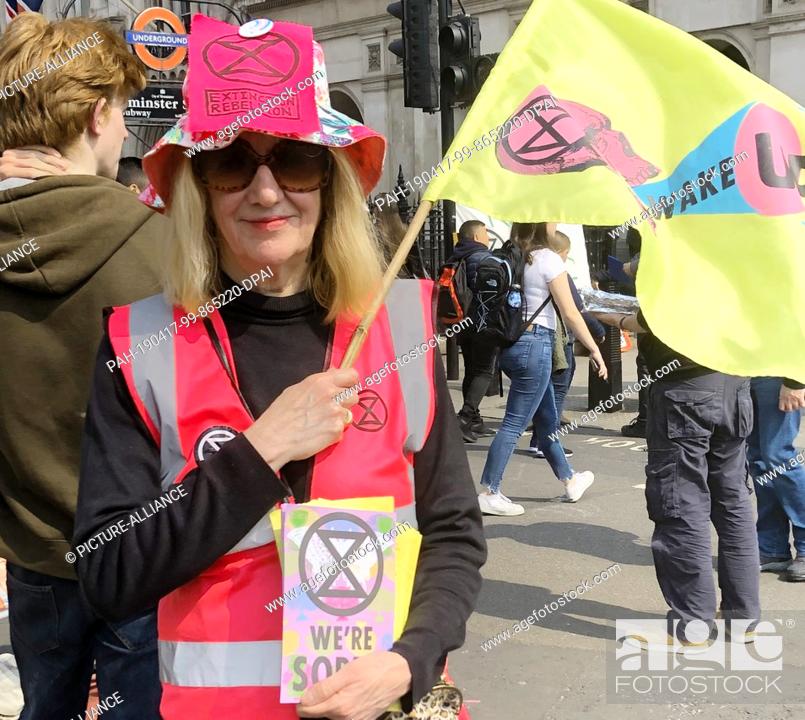 Stock Photo: 17 April 2019, Great Britain, London: Jenn Parkhouse of the Extinction Rebellion movement is waving a yellow flag with the words ""Wake"" during the.
