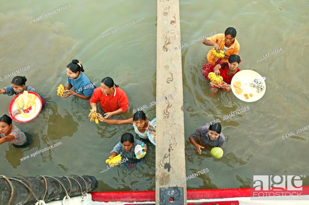 Stock Photo: Women vendors standing waist-high in river, carrying fruit, Myanmar.