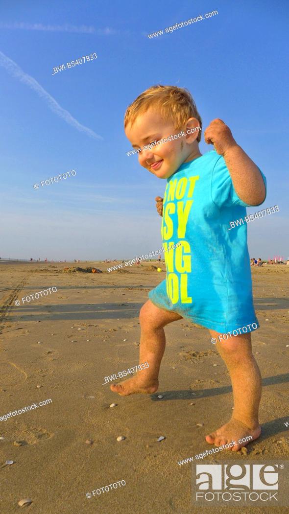 Stock Photo: happy little boy walking on the beach on the North Sea, Netherlands.