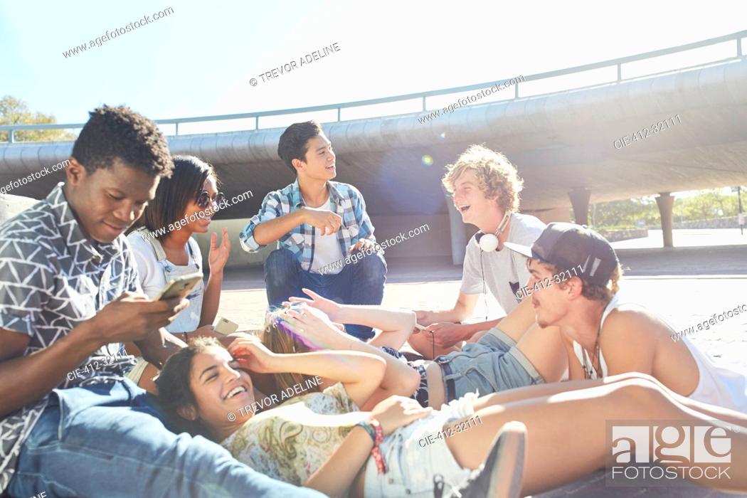 Stock Photo: Teenage friends hanging out at sunny skate park.