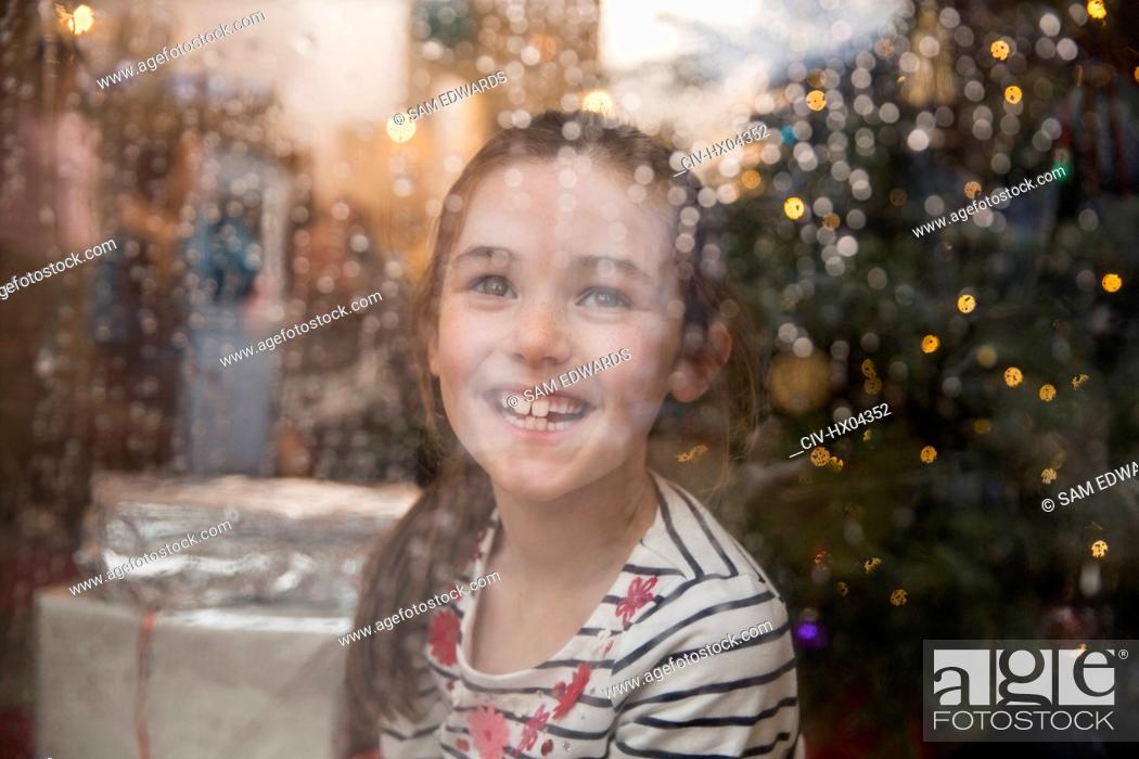 Stock Photo: Portrait happy girl at wet window in Christmas living room.