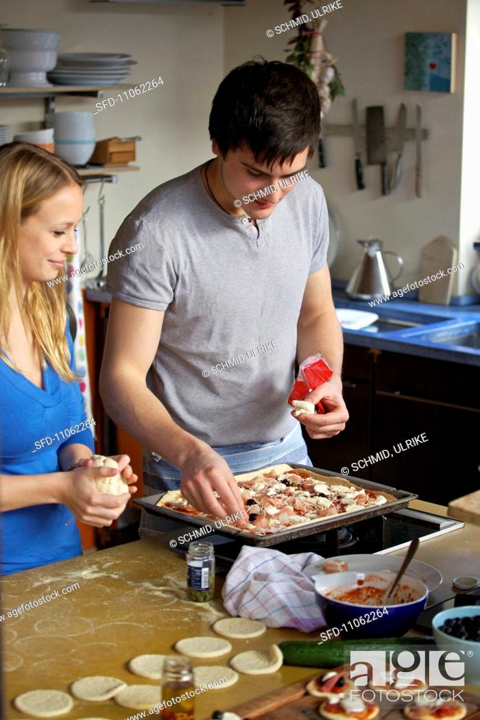 Stock Photo: A young woman and the young man making pizza.