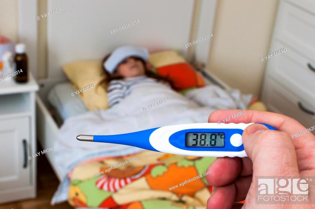 Stock Photo: close up on a digital thermometer that marks 38 degrees Celsius. Little girl into bed with wet cloths on forehead.