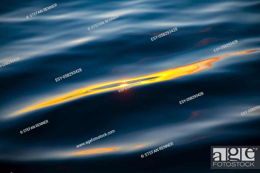 Stock Photo: Light reflected in gold on wave of water on background.