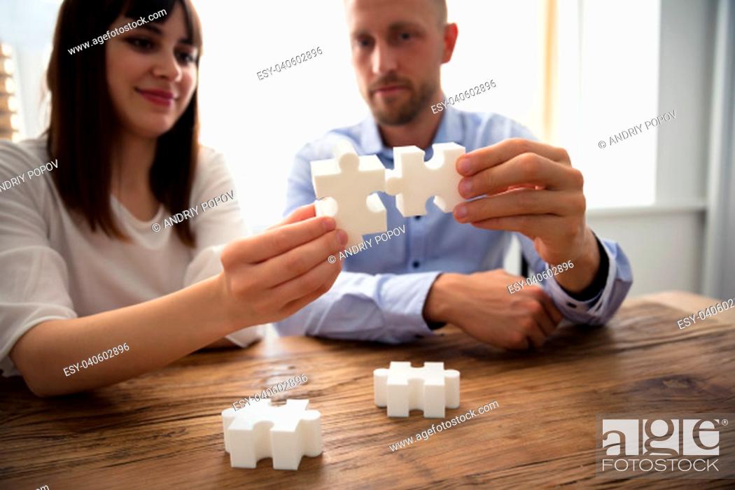 Stock Photo: Close-up Of Two Businesspeople White Jigsaw Pieces Over Wooden Desk.
