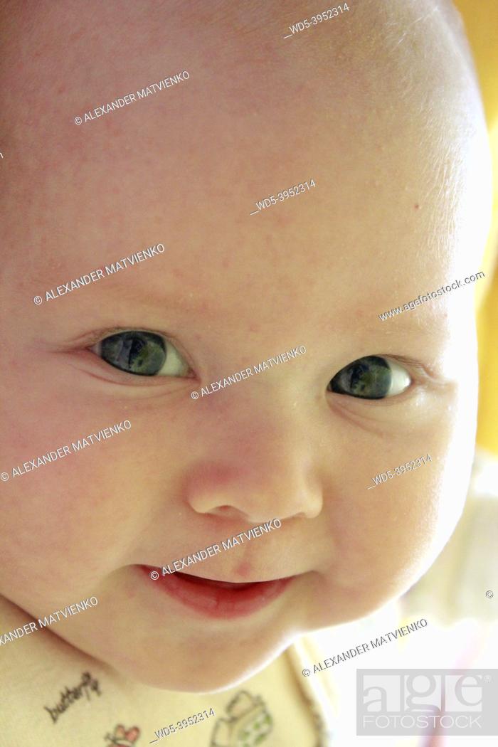 Stock Photo: Portrait of smiling baby with blue eyes. Newborn child looking at mother. Face of newborn baby close up.