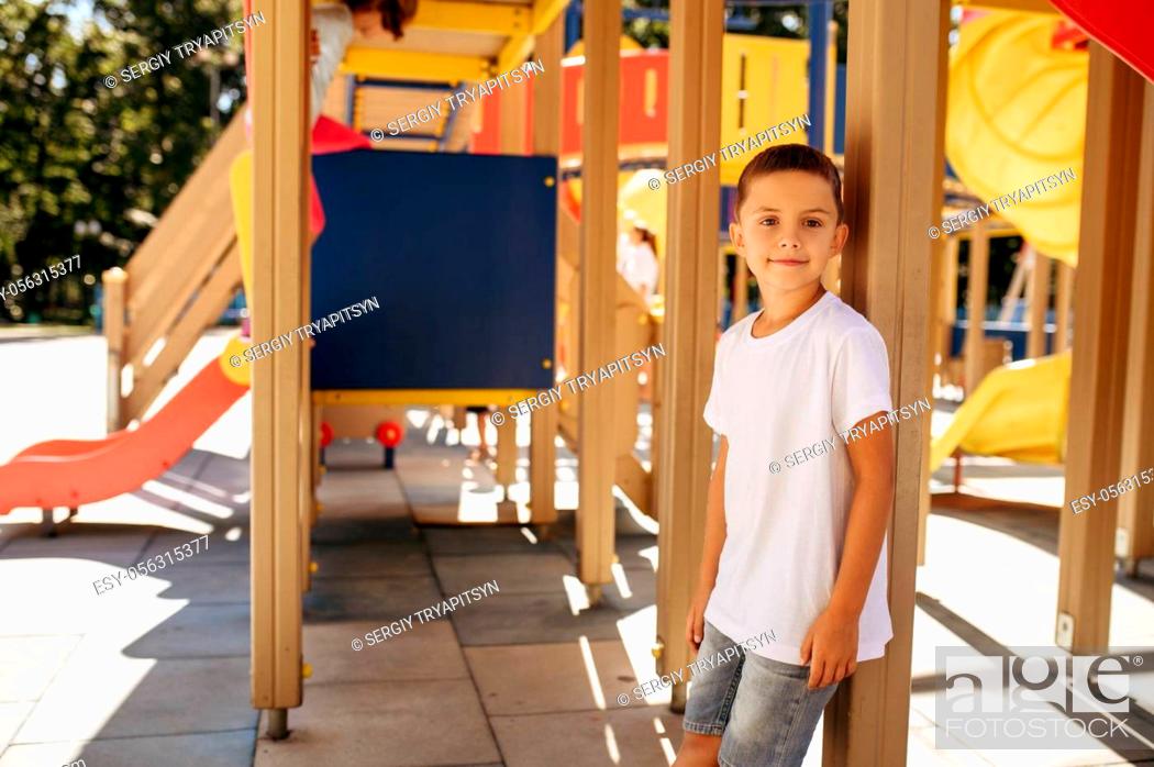Stock Photo: Little boy poses on playground, happy childhood. Child plays on trampoline, extreme sport adventure on vacations, danger entertainment outdoors.