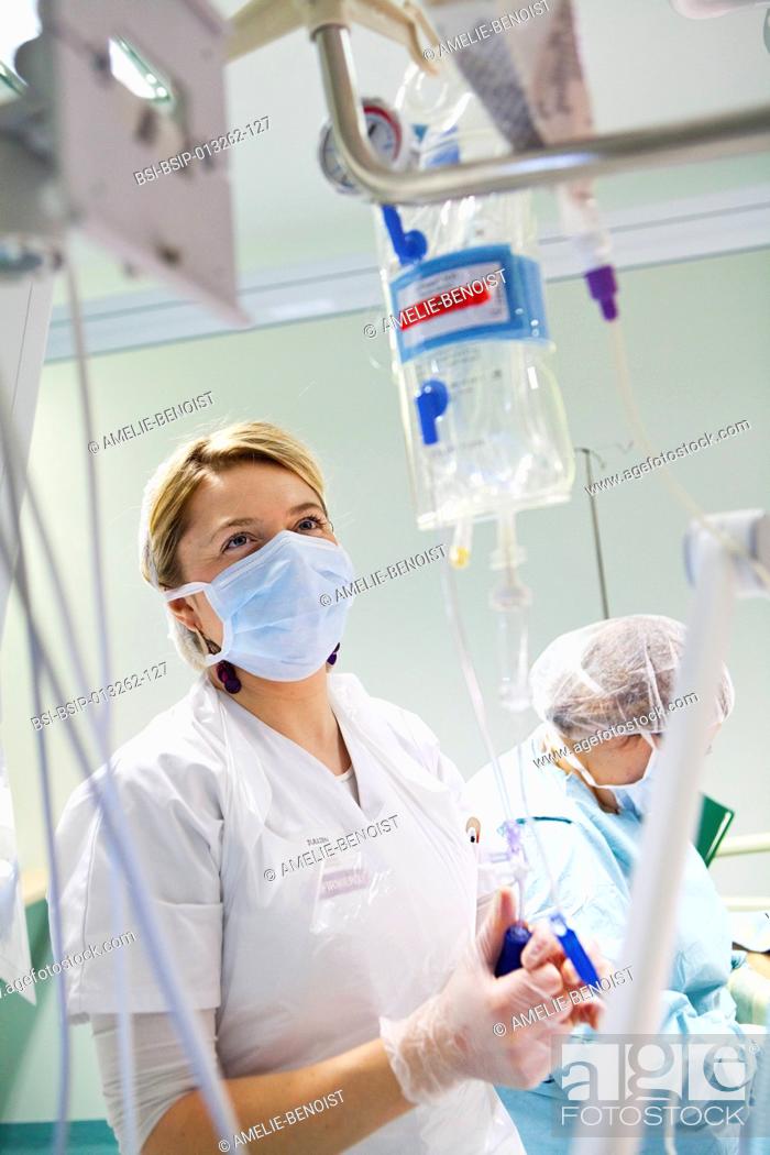 Stock Photo: Reportage in Robert Ballanger hospital's Intensive Care Unit in France. A nurse sets a drip.