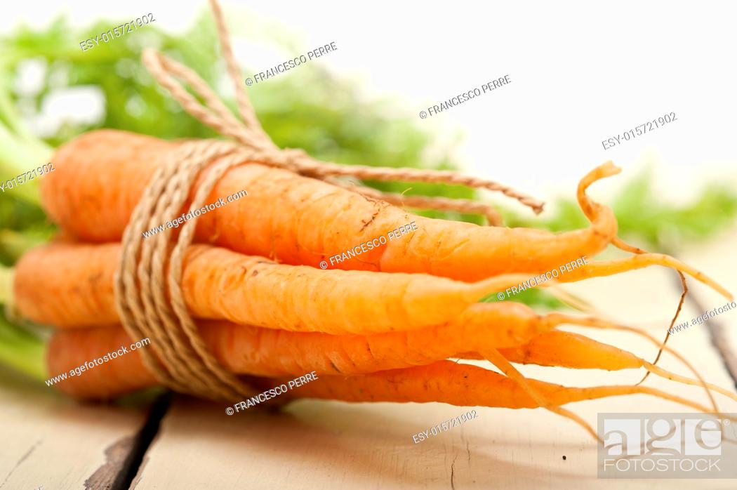 Stock Photo: fresh baby carrots bunch tied with rope on a rustic table.