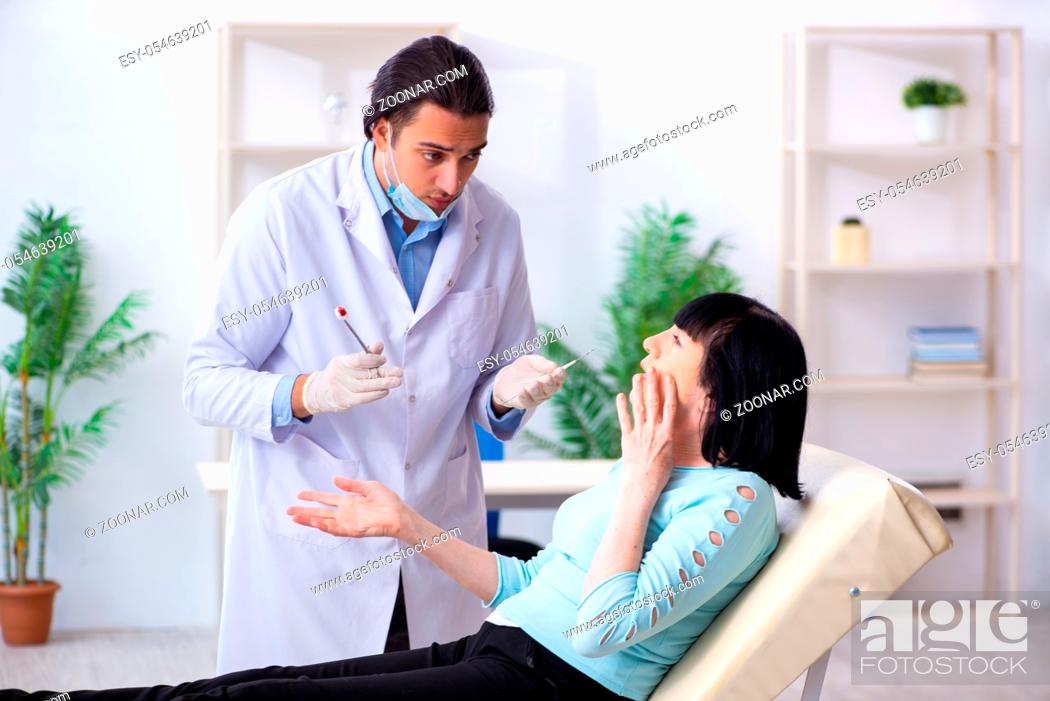 Stock Photo: The old woman visiting young doctor dentist.