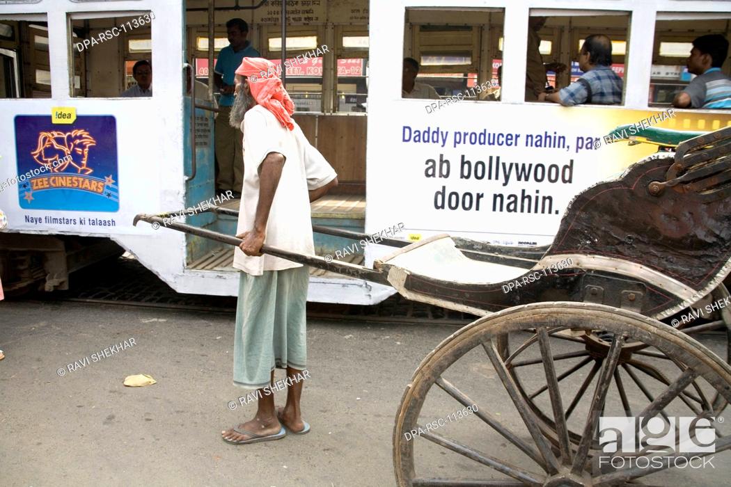 Stock Photo: Manual labor ; hand rickshaw puller standing near tram old way of commuting service ; Calcutta now Kolkata ; West Bengal ; India.